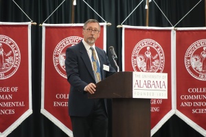 a man giving a lecture at a UA podium