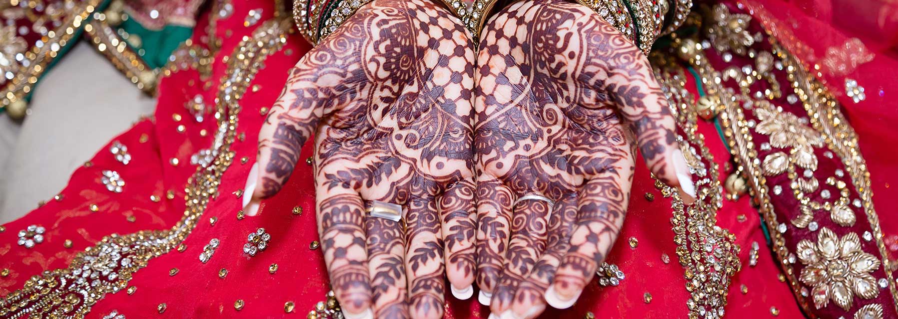 hands with henna tattoos against a bejeweled background